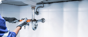 plumber turning wrench on sink pipes